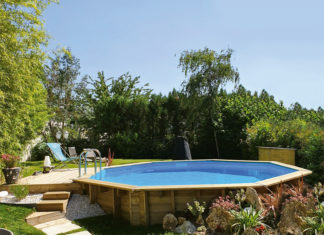 piscina de madera GoForPool, con diseño octogonal, semienterrada en un jardín con terraza en tarima de madera